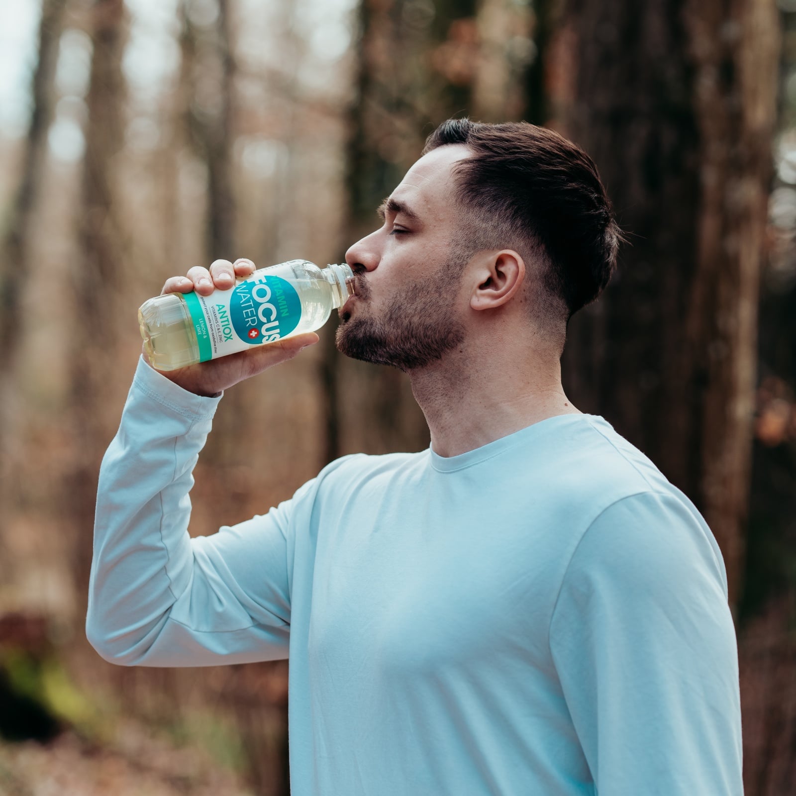 Ein Mann trinkt nach dem Sport im Wald ein Focuswater Antiox Vitaminwasser