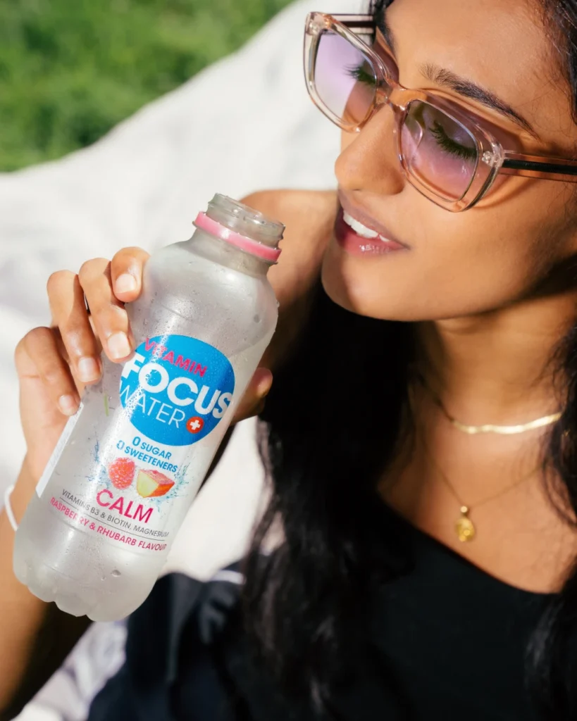 Frau mit Sonnenbrille geniesst Focuswater Calm Himbeer-Rhabarber.