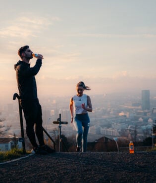 Eine Sportlerin rennt eine Treppe hoch und ihr Trainer trinkt Focuswater Immunity Vitaminwasser