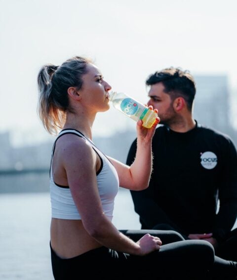 Zwei Sportler machen sitzend pause und trinken ein Focuswater Antiox Vitaminwasser