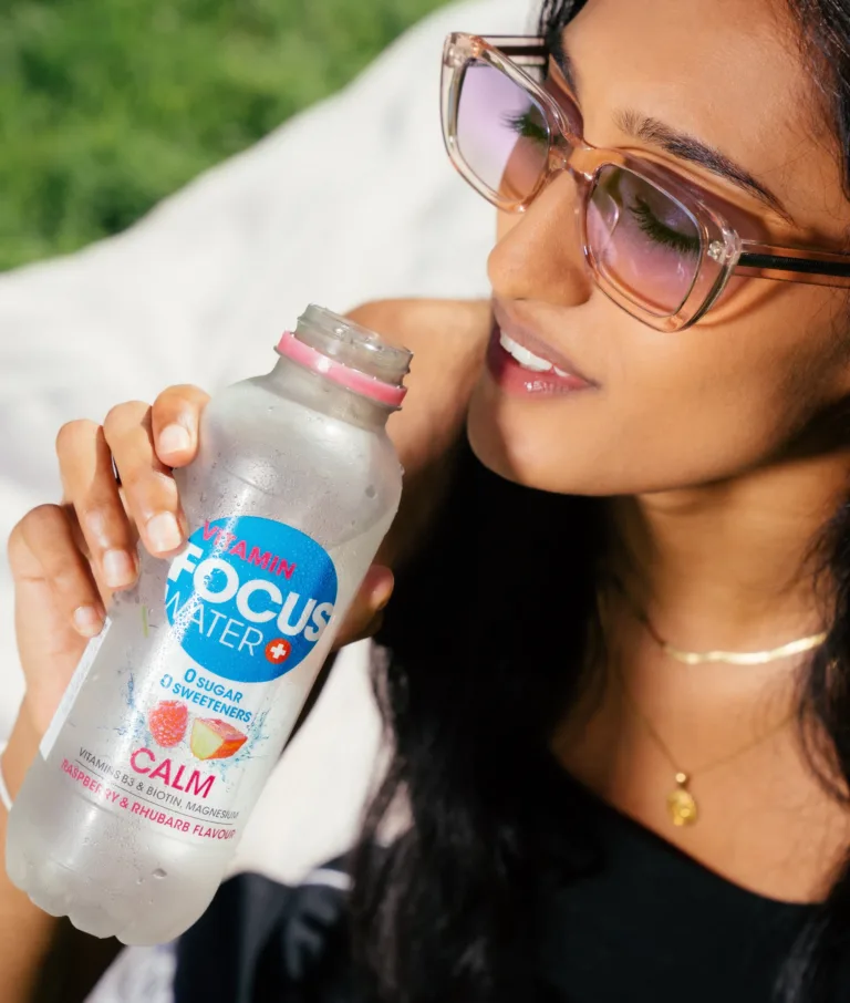 Frau trinkt Focuswater Calm Himbeere Rhabarber im Freien.