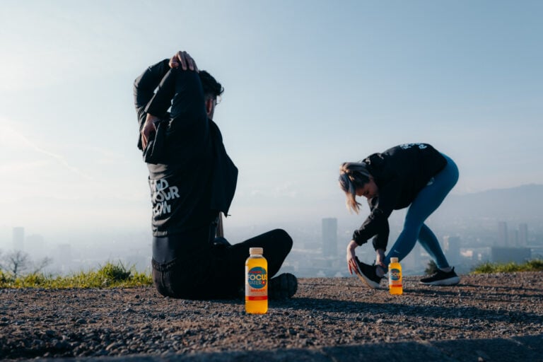 Zwei Personen dehnen sich nach dem Sport und im Vordergrund stehen zwei FOCUSWATER Flaschen