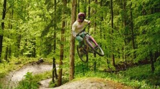 Mountainbikerin springt in grünem Wald.