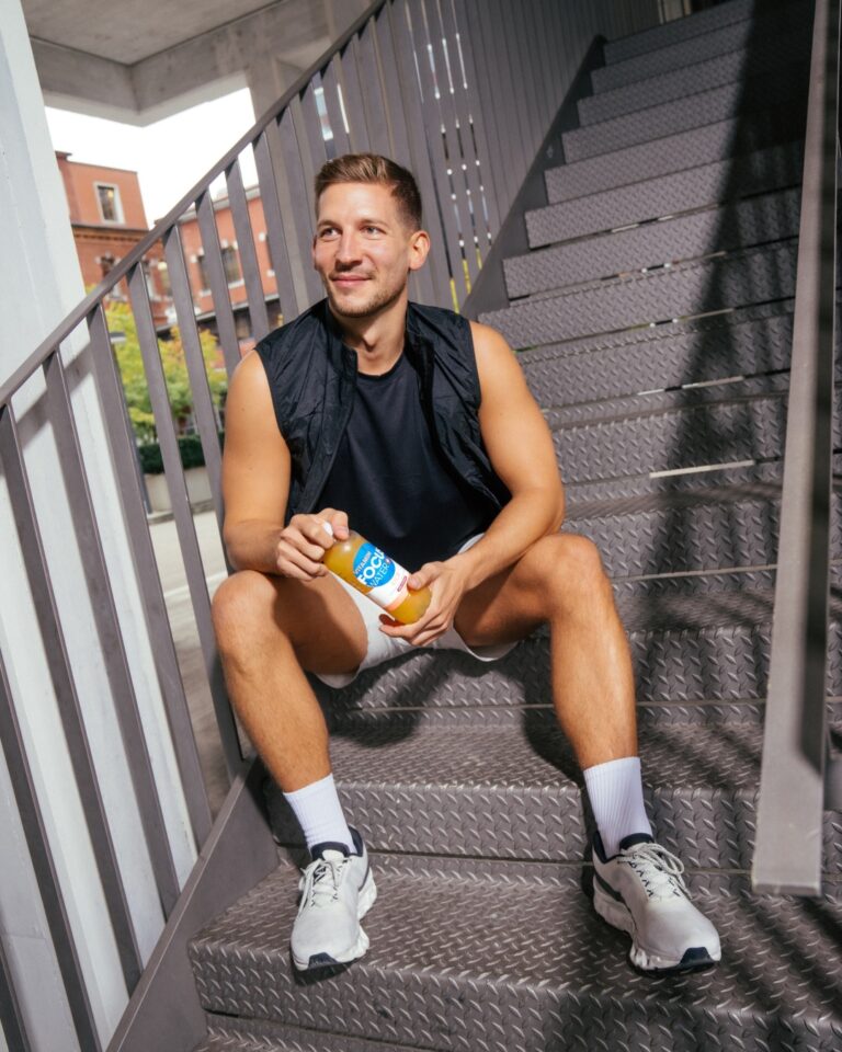 Mann sitzt auf Treppe und hält Focuswater in der Hand.
