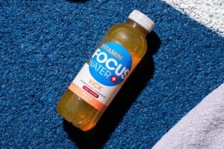 Focuswater Kick Flasche auf blauem strukturiertem Untergrund liegend.