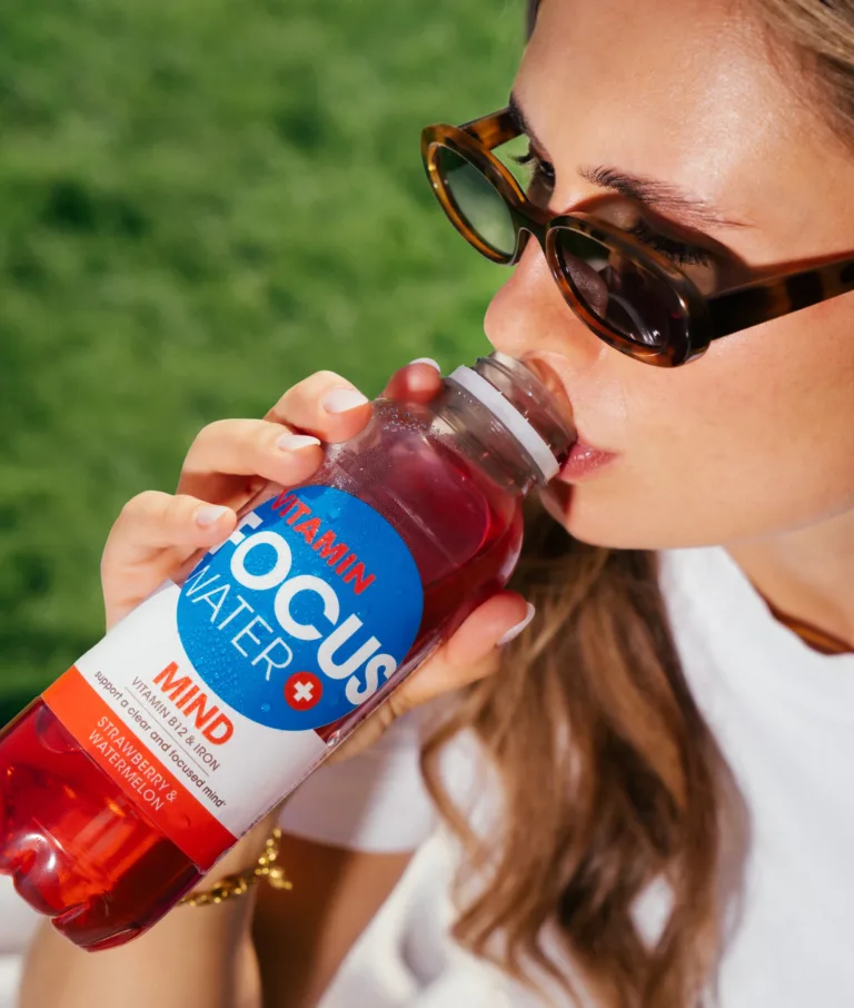 Frau trinkt Focuswater Mind Erdbeere Wassermelone im Freien.