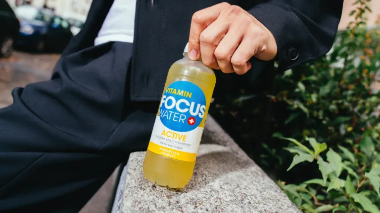 Person hält Focuswater Active Ananas Mango in der Hand, draußen im Freien.