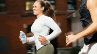Junge Frau joggt mit Focuswater Reload Flasche in der Hand.