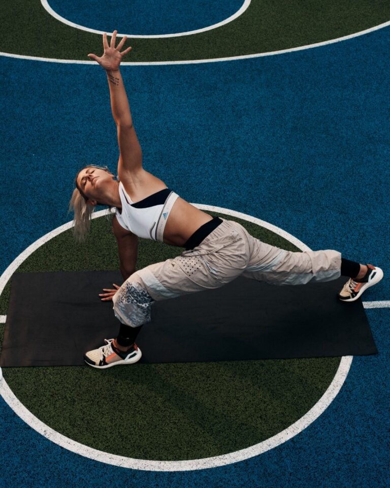 Person beim Yoga-Stretching auf Sportplatz mit blauer Markierung.